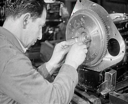 A Coventry factory worker assembling part of an engine.
